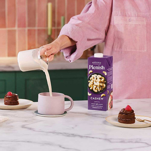 Plenish_Cashew_Nut_Milk_being_poured_into_mug_with_chai_chocolate_cakes