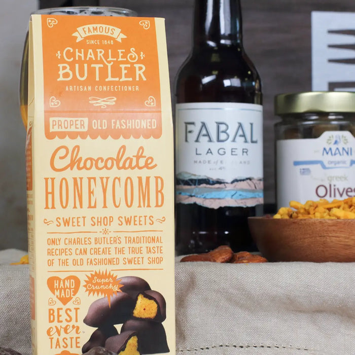 Box of Charles Butler chocolate honeycomb with a bottle of Fabal Lager and a jar of Mani Olives in the background.
