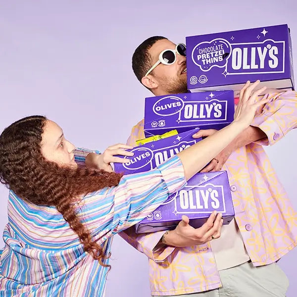 Two people carrying multiple bozes of Olly's snacks olives and pretzel thins