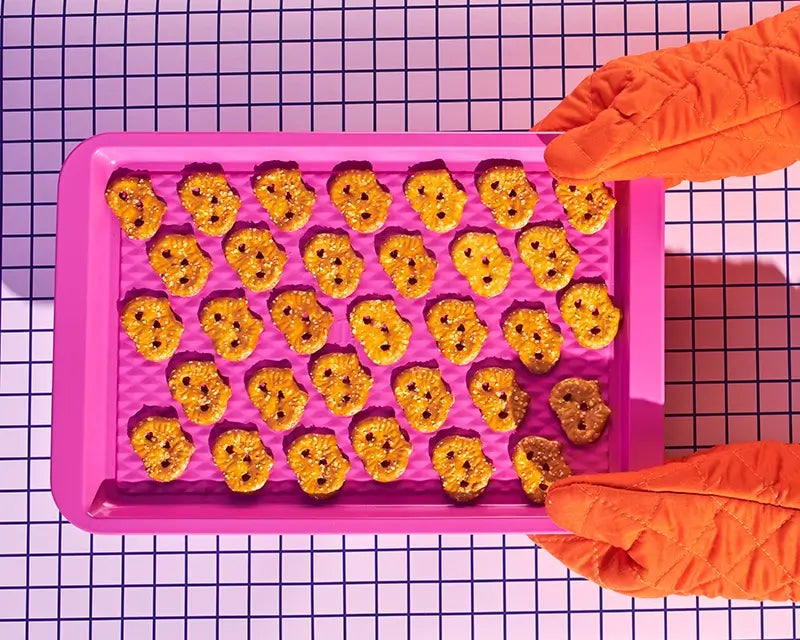 Olly's baked pretzels on a pink tray held by oven gloved hands
