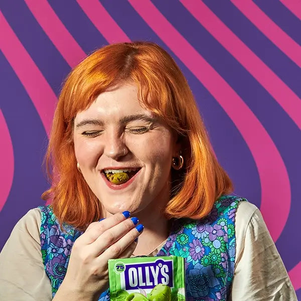 Olives woman laughing with Olly's basil olives in mouth and holding snack pouch