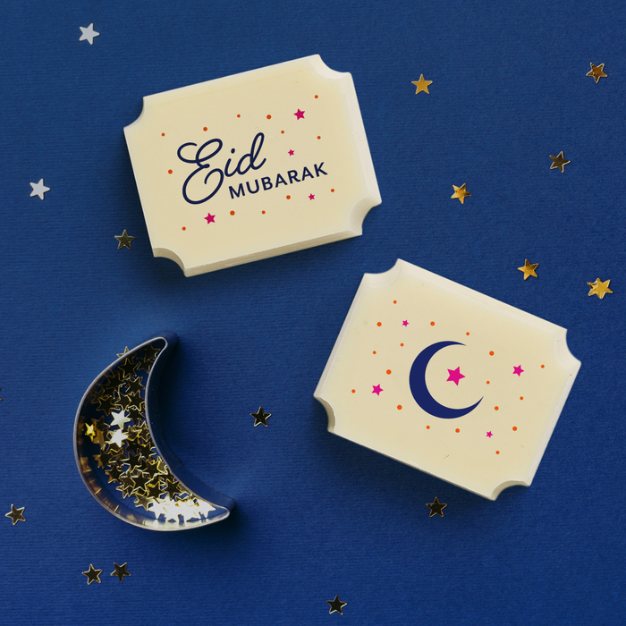 Two white chocolates filled with dark chocolate ganache, made by Harry Specters, with printed Eid Mubarak designs.