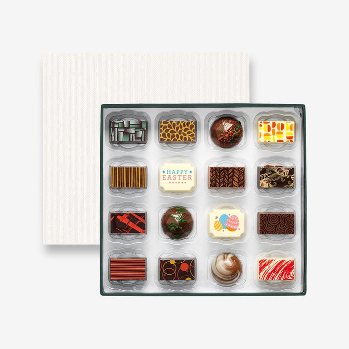 An open chocolate selection box containing 16 chocolates made by Harry Specters. The chocolates seen within this gift box are a colourful mix of white, milk, and dark chocolate with two Happy Easter message chocolates.