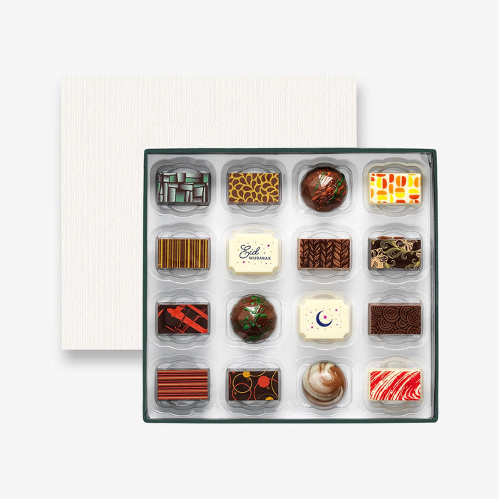 An open chocolate selection box containing 16 chocolates made by Harry Specters. The chocolates seen within this gift box are a colourful mix of white, milk, and dark chocolate with two Eid Mubarak message chocolates.