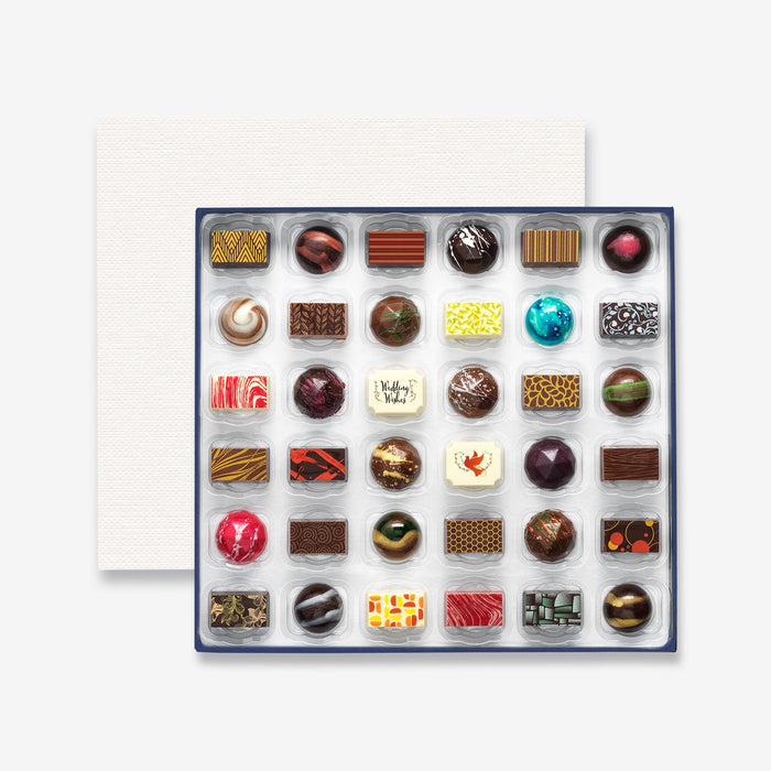 An open chocolate selection box containing 36 chocolates made by Harry Specters. The chocolates seen within this gift box are a colourful mix of white, milk, and dark chocolate with two Wedding Wishes message chocolates.